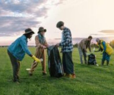 A diverse group of volunteers collecting trash in a field at sunset, promoting environmental awareness.