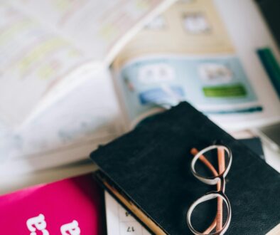 A study setup with a Spanish grammar book, calendar, and eyeglasses on a desk, suggesting focused learning.