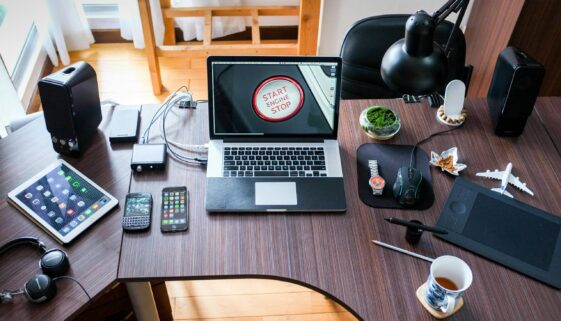 A contemporary office desk setup with laptops, gadgets, and accessories, creating a tech-savvy workplace.