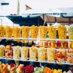 Vibrant display of fresh fruit cups at a sunny outdoor market.