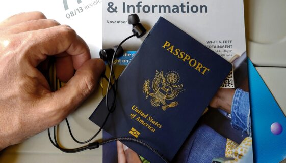 Close-up of US passport with inflight magazine and headphones on an airplane seat, ready for travel.